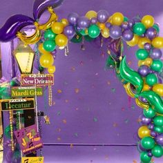 a mardi gras arch with balloons and streamers on the side for decoration