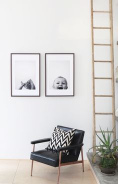 two framed pictures hang on the wall next to a chair with a black and white pillow