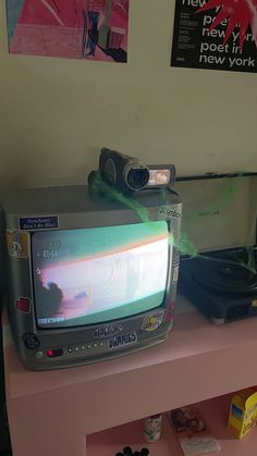 an old tv sitting on top of a pink shelf