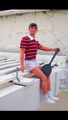 a young man sitting on top of a white bench holding a racquet and ball