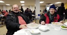 two people sitting at a table with plates of food