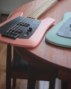 two guitars sitting on top of a wooden table next to each other, one is green and the other is blue