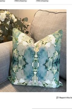 a blue and green pillow sitting on top of a gray couch next to a potted plant