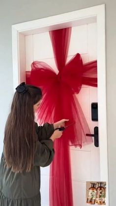 a woman is painting a red bow on the door