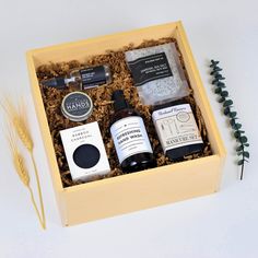 an open wooden box containing three bottles of essentials and a plant next to it