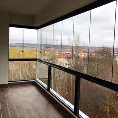 an empty room with large glass windows overlooking the cityscape and trees in the distance