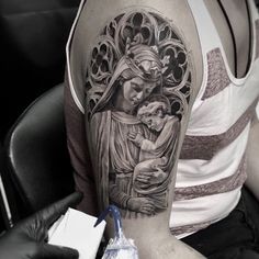 a man with a tattoo on his arm holding a baby jesus and an ornate frame