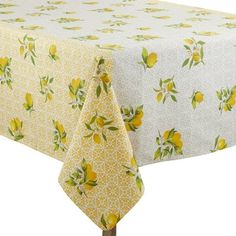 a yellow table cloth with lemons and leaves on it, sitting on top of a wooden stand