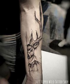 a black and white tattoo with a deer head on the left side of the arm