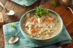 a bowl of soup with carrots, meat and parsley in it on a blue napkin