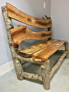 a wooden bench made out of logs sitting in a room with concrete flooring and walls