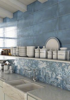 a kitchen with blue tiles and white dishes on the shelf above the sink in front of it