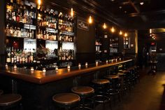 a dimly lit bar with lots of bottles on the shelves