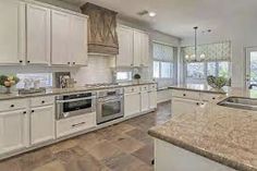 a large kitchen with white cabinets and granite counter tops