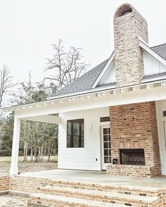 a white house with a brick chimney on the front porch