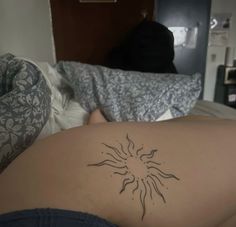 a woman laying in bed with a tattoo on her stomach and the sun behind her