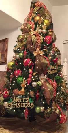 a decorated christmas tree in a living room with gold and red ornaments on the top