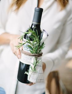 a woman holding a bottle of wine with a plant in it