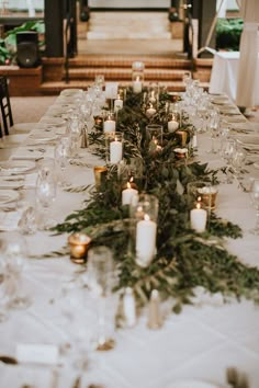 a long table is set with candles and greenery for a formal dinner or reception