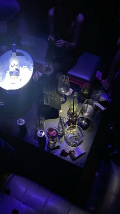 people sitting around a table with wine glasses and bottles on it, in the dark