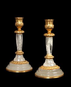 two gold and glass candlesticks are on display in front of a black background