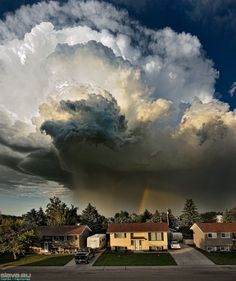 a large cloud is in the sky over some houses