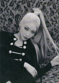 black and white photograph of a woman with long blonde hair sitting on a couch in front of a wall