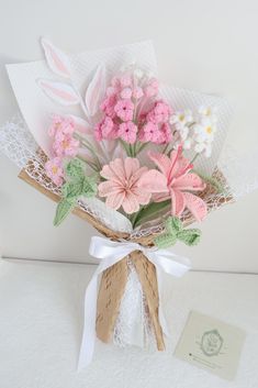 a bouquet of flowers sitting on top of a white table next to a card and envelope