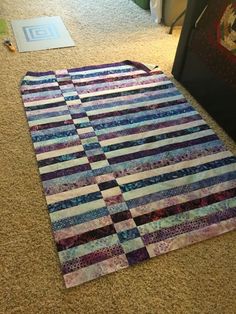 a quilt laying on the floor next to a rug