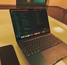 an open laptop computer sitting on top of a table next to a cell phone and tablet