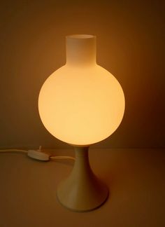 a white lamp sitting on top of a table next to a light plugged in