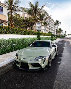 a white sports car parked on the side of the road in front of palm trees