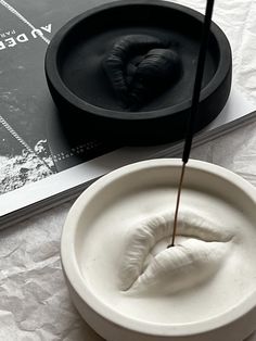 a white bowl sitting on top of a table next to a book and an object