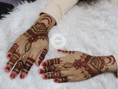 two hands with hendi designs on them sitting on a white furnishing area