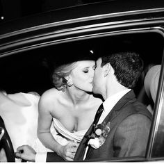 a bride and groom kissing in the back seat of a car at their wedding reception