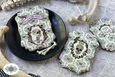 decorated cookies are on a plate and next to an animal skull, skeleton head, and bone bones