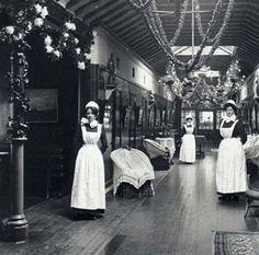 an old black and white photo of women in maid outfits standing in front of beds