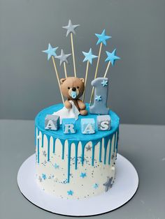 a blue and white cake with a teddy bear on top