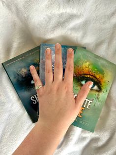 a person's hand on top of two books