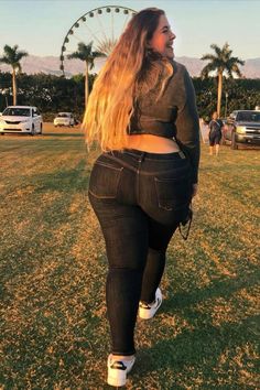 A casual scene at golden hour featuring a woman walking on a sunlit lawn, dressed in fitted jeans and a dark top. A Ferris wheel, palm trees, and parked cars create a festival-like atmosphere in the background. Coachella Vibes, Trendy Plus Size Fashion, Festival Inspiration, Festival Vibes, Festival Outfits, Perfect Outfit, Plus Size Fashion, Boho Chic, Long Hair Styles