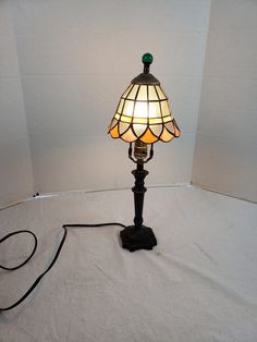 a lamp that is on top of a white sheeted floor with a cord attached to it