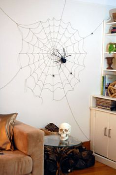 a spider web is hanging on the wall next to a couch and table with yarn