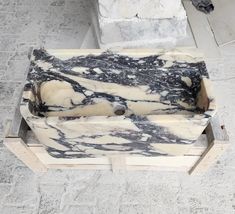 a marble sink sitting on top of a wooden stand in the middle of a floor