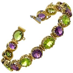 This exquisite 18k yellow gold tennis bracelet features over 33 carats of amethyst and peridot in luscious jewel-toned grape colors! Each round amethyst and oval peridot is showcased in its own gorgeous 18k yellow gold setting that is as beautiful from the side view as well as from the top. The scalloped basket design showcases both the fine gemstones and the artisan skill used to create this unique piece of jewelry. The clasp includes a safety chain for added security. Such a vibrant bracelet, full of life! Imagine yourself in a warm, sunny vineyard, sipping a glass of sparkling wine, wearing this exquisite, sparkling bracelet! Salut! Bracelet measures 7.50 inches in length Amethysts, 8.00mm, 12.60 carat total Peridots, 10.00 x 8.00mm, 21.05 carat total Amethyst And Peridot, Peridot Bracelet, Sparkle Bracelet, 18k Gold Bracelet, Peridot Jewelry, Cord Jewelry, Indian Jewellery Design Earrings, Necklace Cord, Purple Jewelry