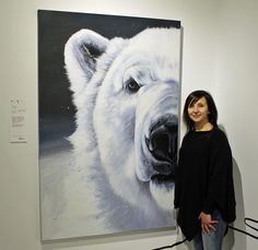 a woman standing next to a painting of a white bear