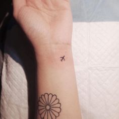 a person's arm with a small tattoo that has an airplane on the wrist