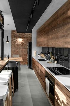 a modern kitchen with wooden cabinets and white counter tops, along with bar stools