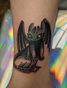 a small dragon tattoo on the ankle, with yellow eyes and an eyeball in its mouth