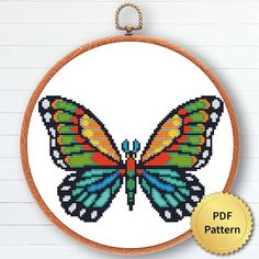 a colorful butterfly cross stitch pattern on a white background with a gold medal around it