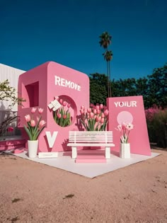 a white bench sitting in front of a pink building with flowers growing out of it